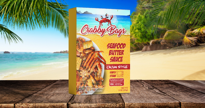 Crabby Bags Garlic Butter Sauce package on a beach background, featuring Cajun Seafood Butter Sauce.